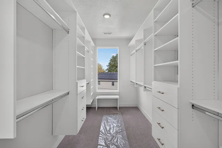 Custom closet system featuring white built-in shelving, hanging rods, and drawers