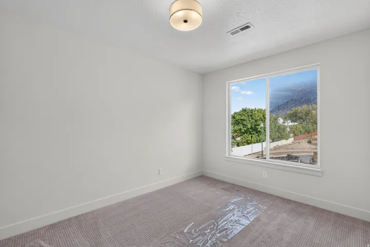 Neutral wall color, wall-to-wall carpeting, recessed ceiling light fixture, large window, and white trim