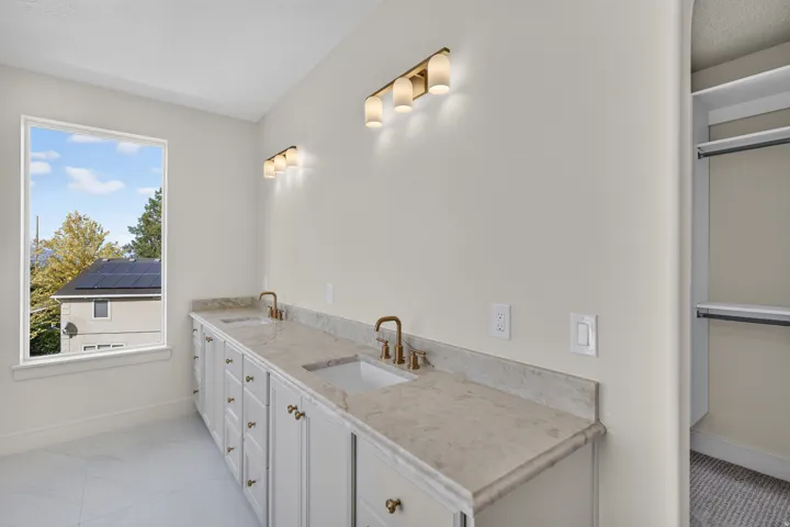 Dual vanity with undermount sinks, bronze finish fixtures, and light-toned countertops