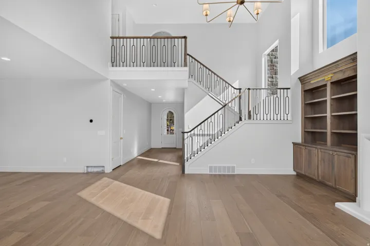 Dramatic two-story foyer showcasing soaring ceilings, a floating staircase with metal railings, and abundant natural light from expansive windows