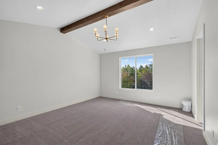 Primary Bedroom with Vaulted ceiling featuring a wood-finish beam, recessed lighting, and a chandelier