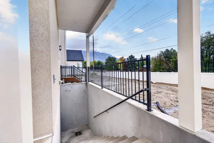 Basement Entrance with Covered concrete patio with recessed lighting, leading to a concrete staircase with a black metal handrail