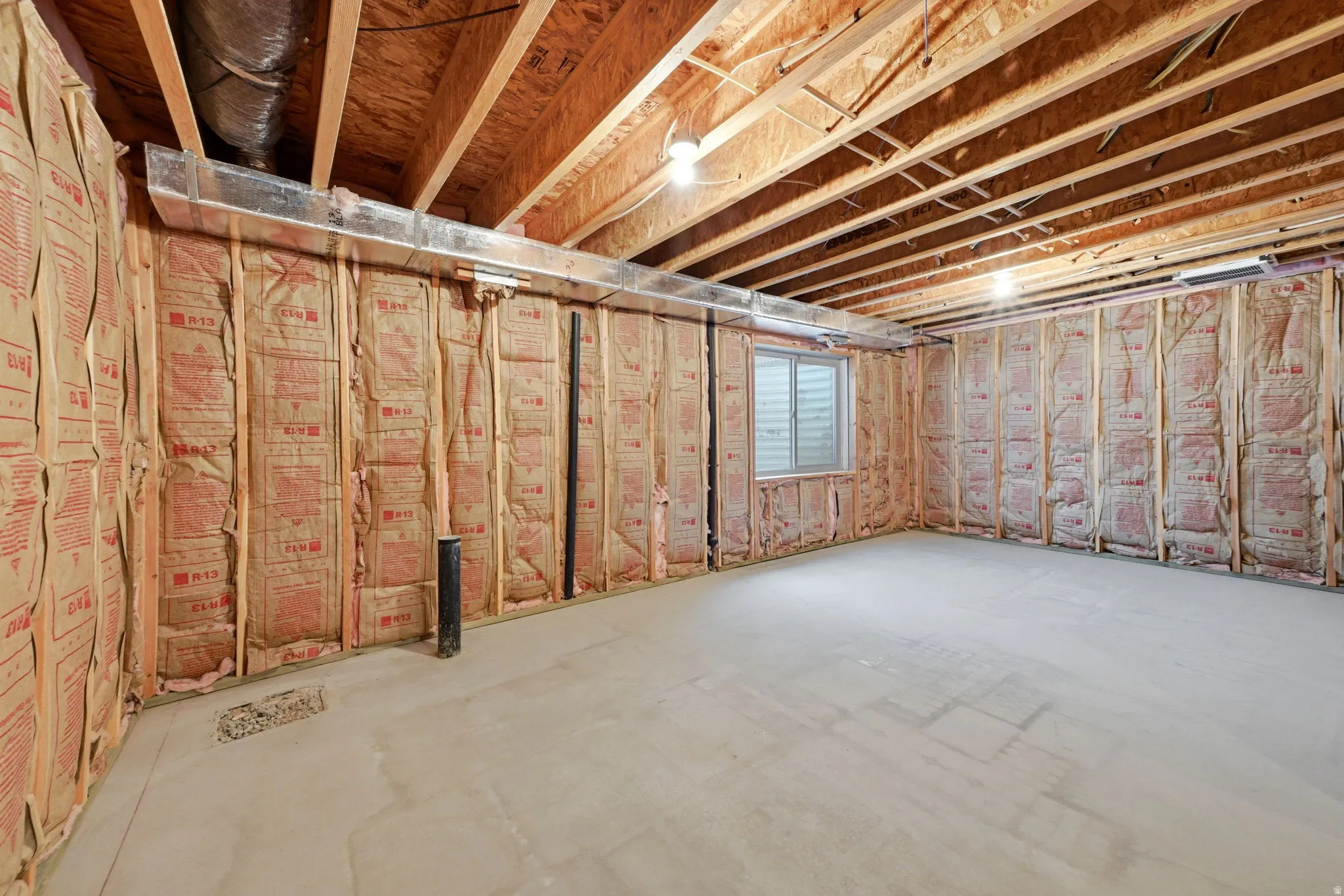 Unfinished basement area featuring exposed wood framing, ceiling joists, and concrete flooring