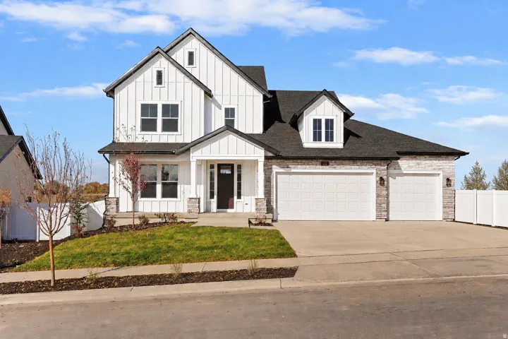Modern farmhouse exterior featuring white board and batten siding, stone facade accents, a dark asphalt shingle roof, and a three-car garage