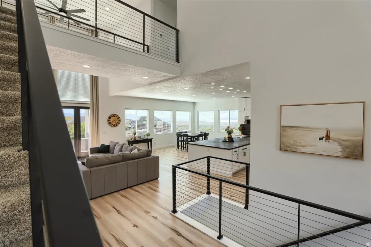 Open-concept living space featuring high ceilings, wood-finish flooring, and abundant natural light from multiple windows and glass doors