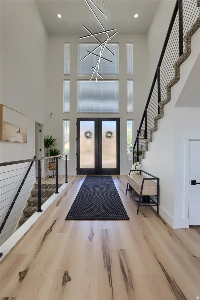Grand two-story foyer featuring a striking modern chandelier and light wood-finish flooring