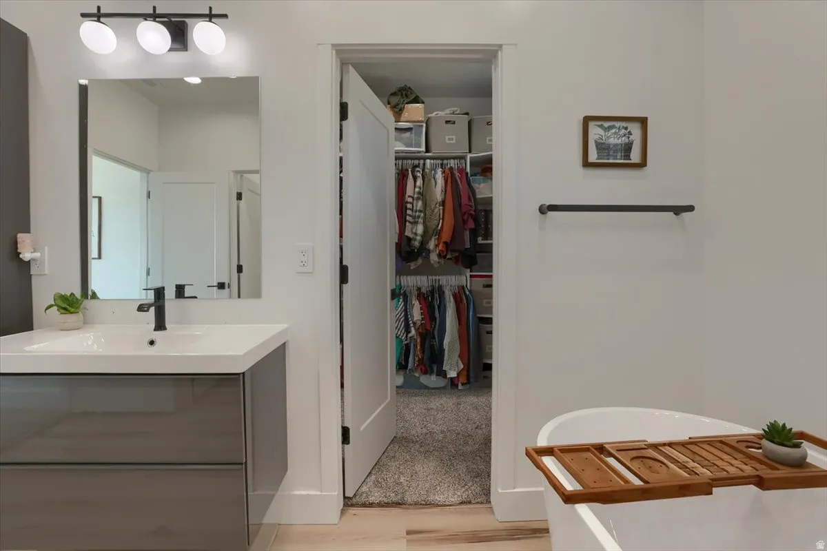 Modern bathroom featuring a floating vanity with a vessel sink and matte black faucet, a large rectangular mirror, and contemporary three-bulb vanity lighting