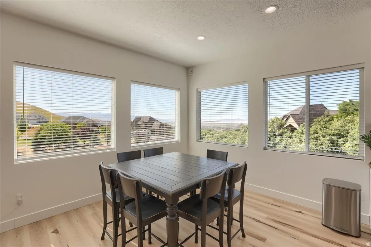 Bright interior featuring multiple large windows, recessed lighting, light wood-finish flooring, and crisp white baseboards