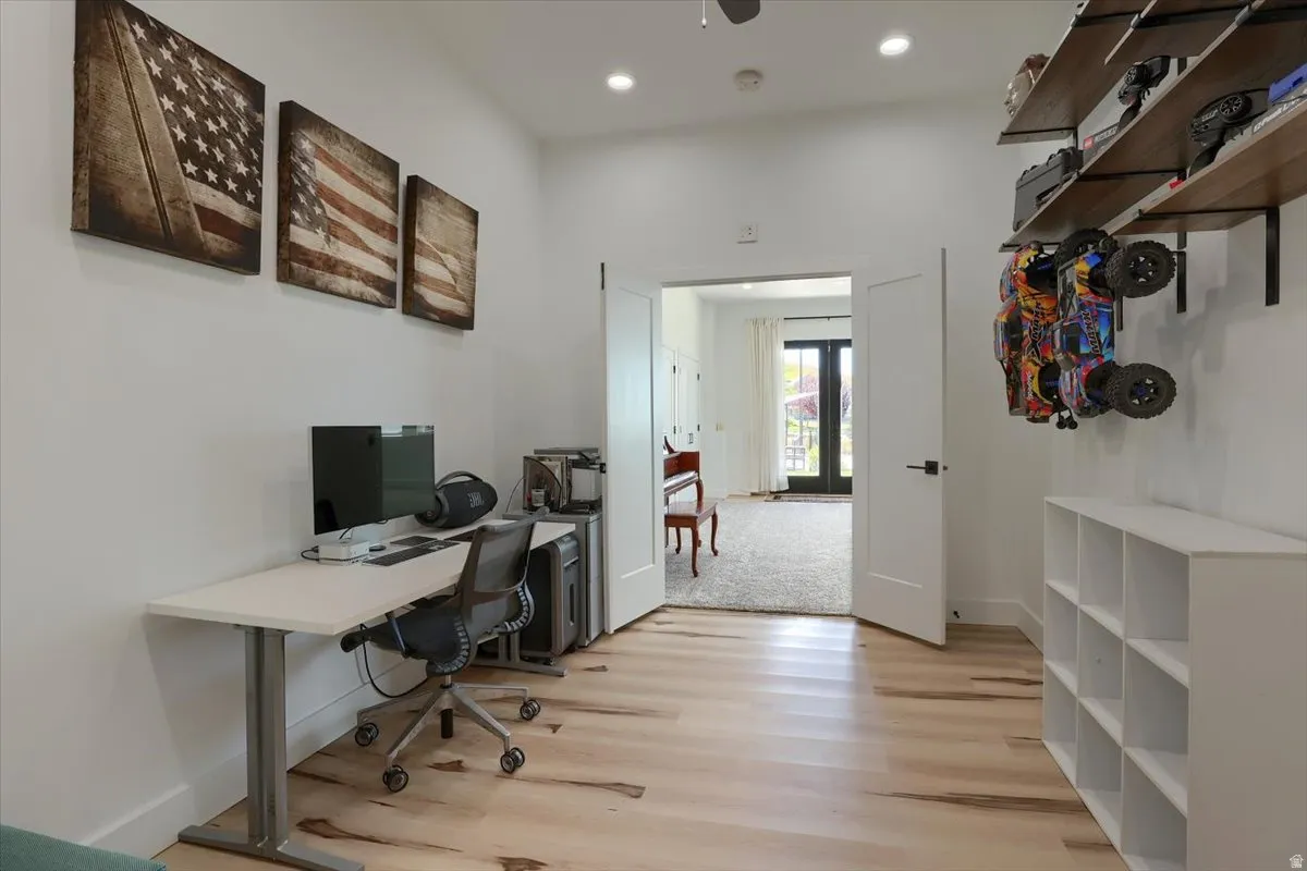 Hardwood-style flooring with bright white walls, recessed lighting, and a doorway leading to an additional space with double doors