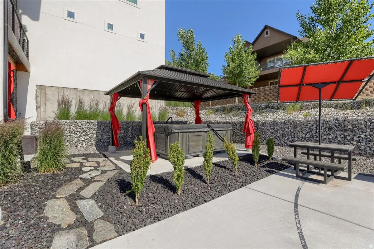 Outdoor patio featuring a covered hot tub, flagstone path, and a gabion wall