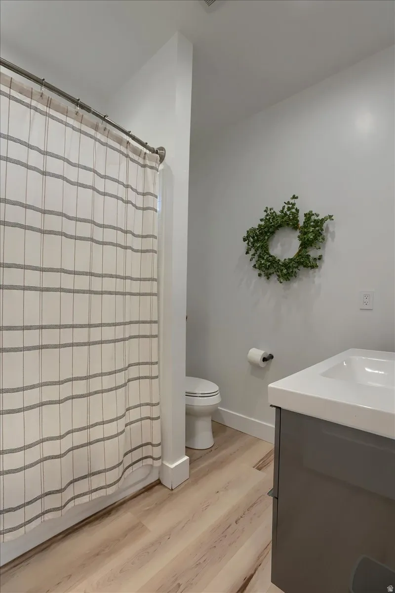 Full bathroom featuring a shower with a striped curtain, a white toilet, and a gray vanity with a white countertop and integrated sink