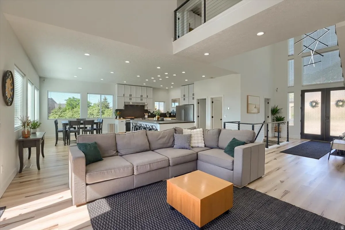 Open-concept living area with light wood-finish flooring, high ceilings, and recessed lighting
