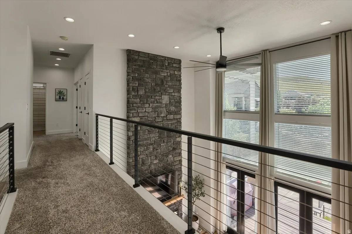 Upper-level walkway featuring carpet flooring and modern cable railings