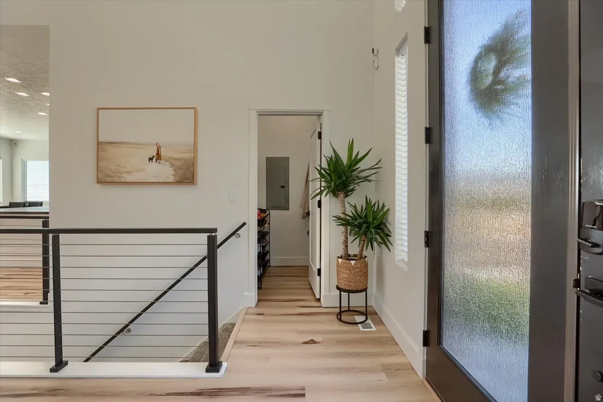 Entryway featuring light wood-finish flooring and a contemporary black metal railing with horizontal balusters