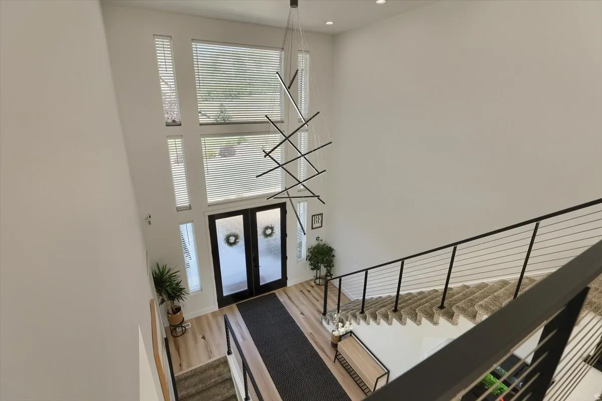 Two-story foyer featuring a contemporary chandelier, abundant natural light from multiple windows, and a cable railing staircase