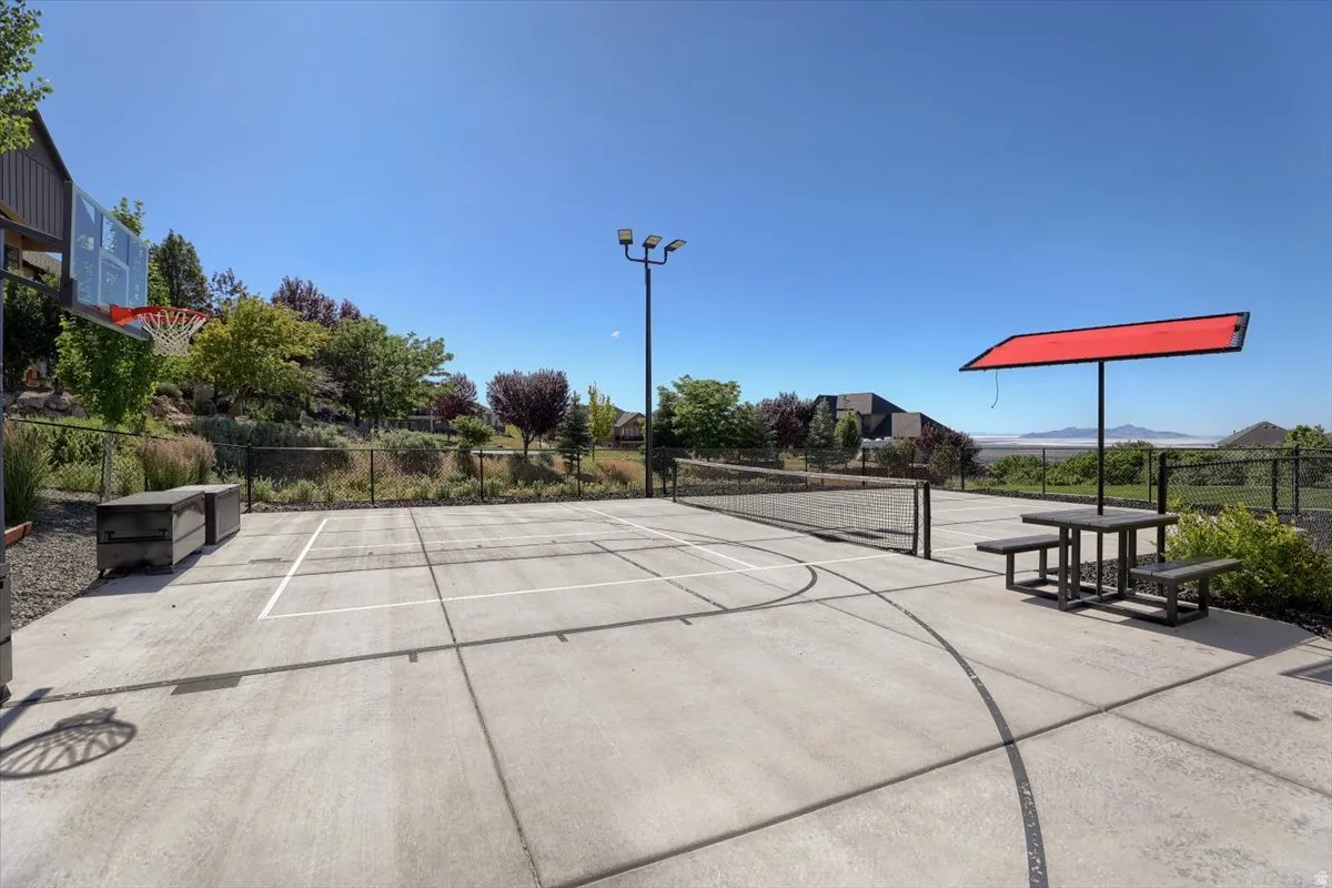 Concrete sport court featuring a basketball hoop and net