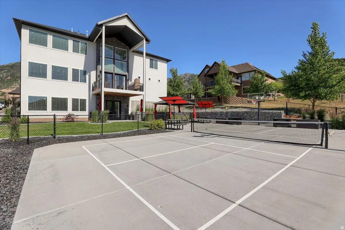 Concrete sports court with permanent net, bordered by dark gravel and a chain link fence