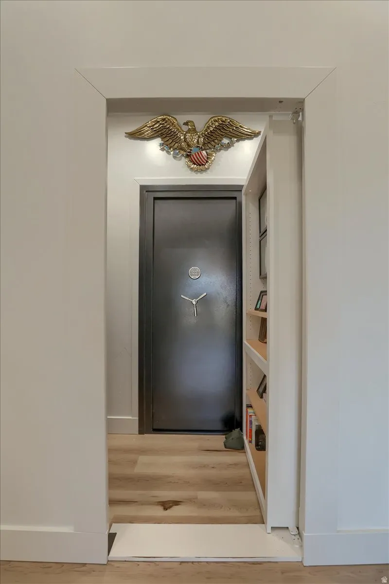 Light wood-finish flooring extending into a discreetly recessed area, featuring a heavy-duty vault door