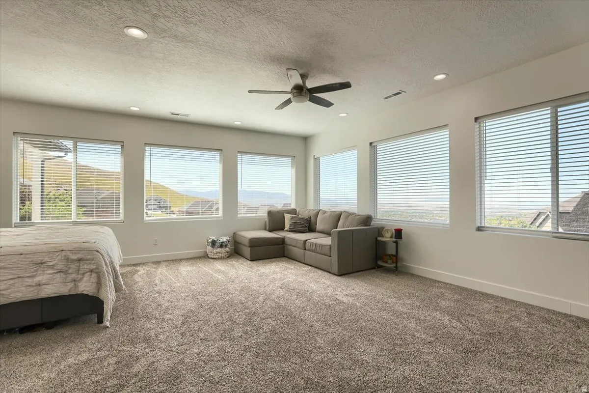 Spacious room featuring abundant natural light, recessed lighting, a ceiling fan, and extensive carpeting