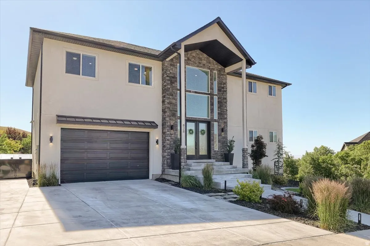 Contemporary residence featuring a prominent stone facade entrance with a two-story window array