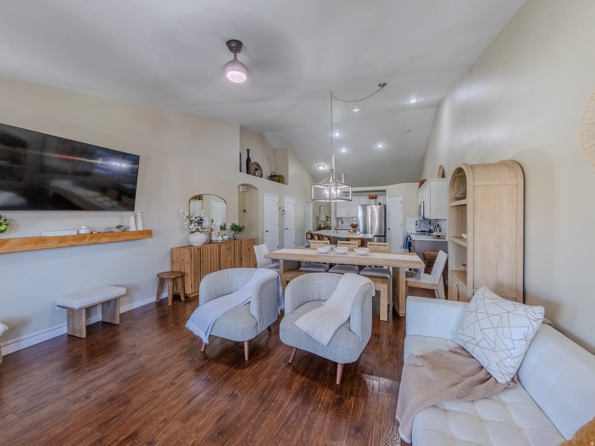 Open-concept living space featuring wood-finish flooring, recessed lighting, and a vaulted ceiling