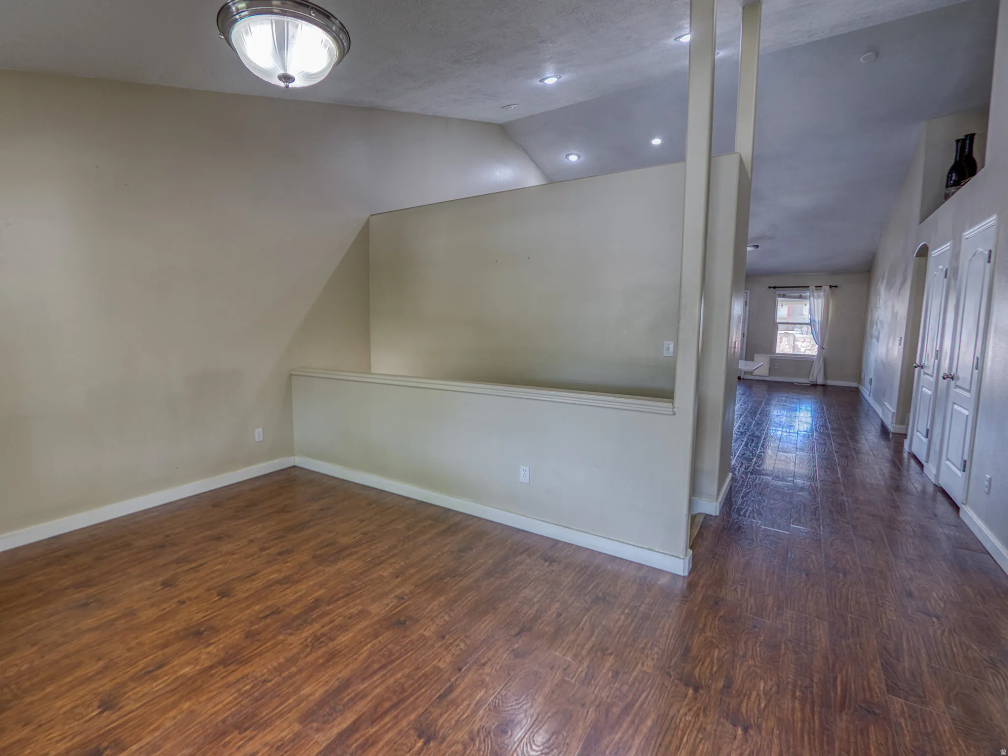 Wood-finish flooring throughout, featuring a vaulted ceiling and recessed lighting