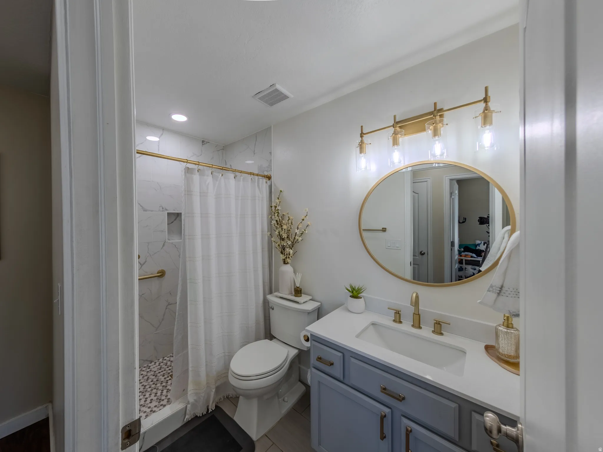 Bathroom featuring a shower with white marble-look tile, pebble flooring, and a built-in niche