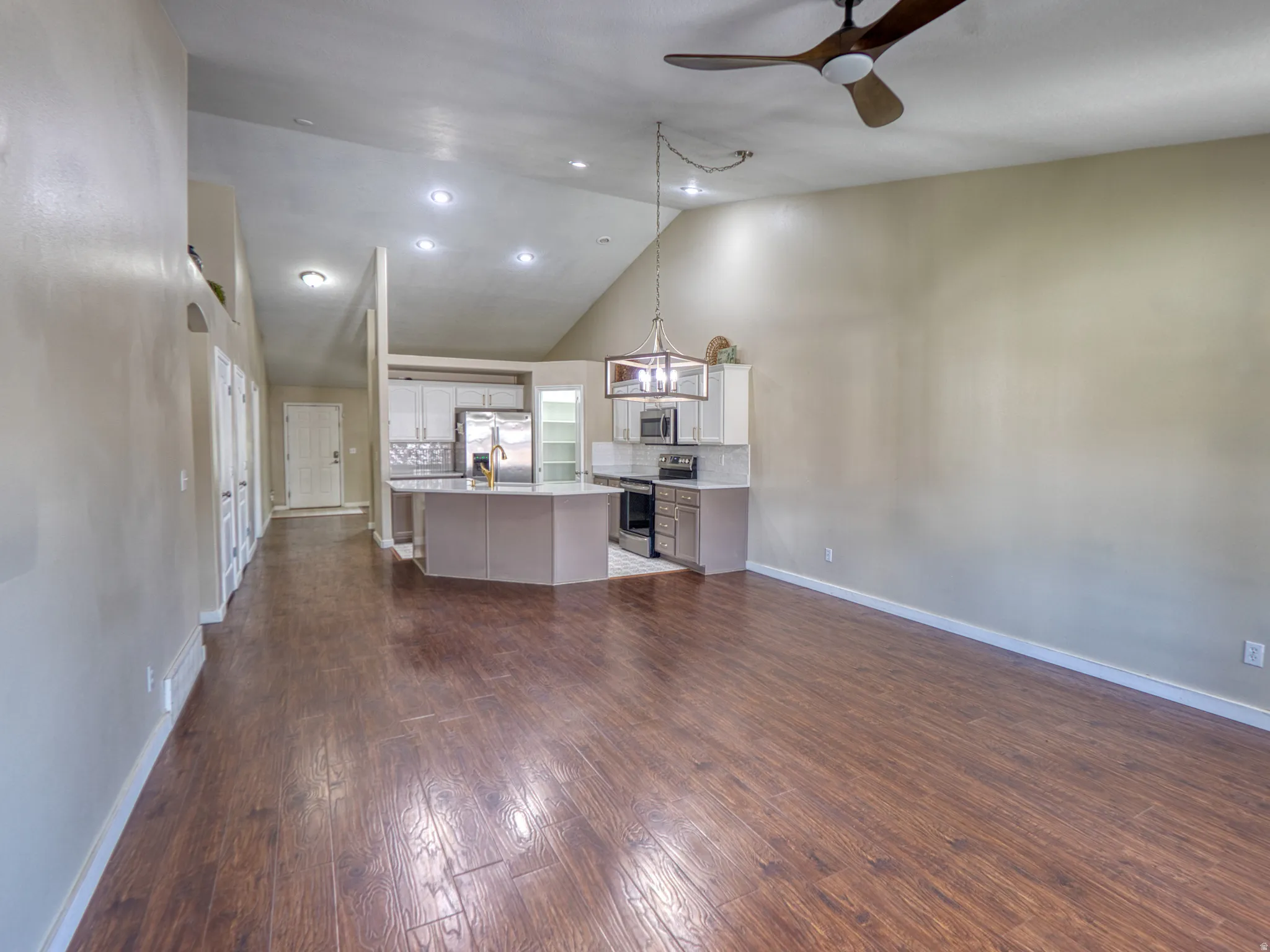 Open-concept living space featuring vaulted ceilings, wood-finish flooring, and a contemporary ceiling fan