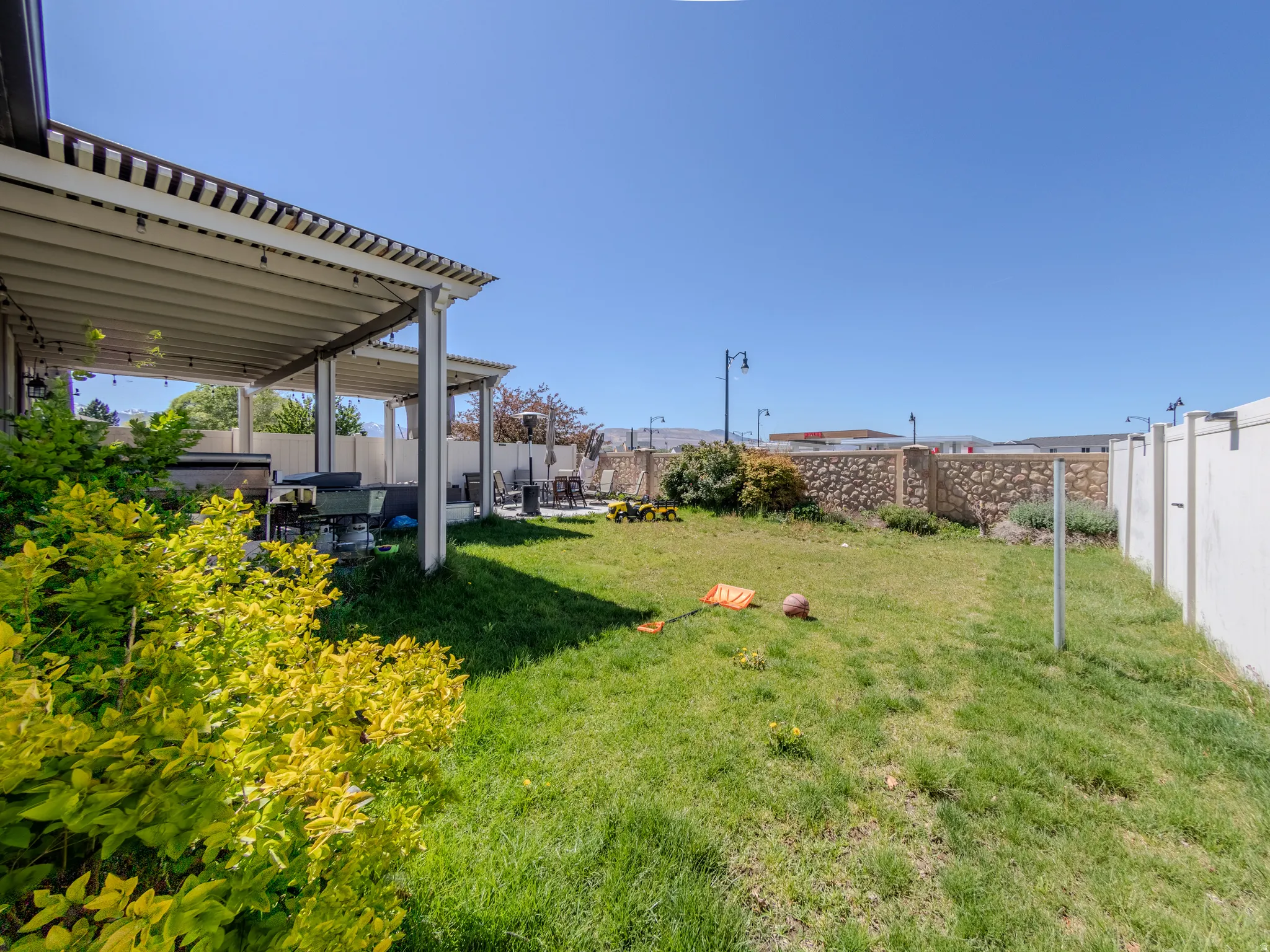 Spacious backyard featuring a covered patio, extensive lawn area, and privacy fencing