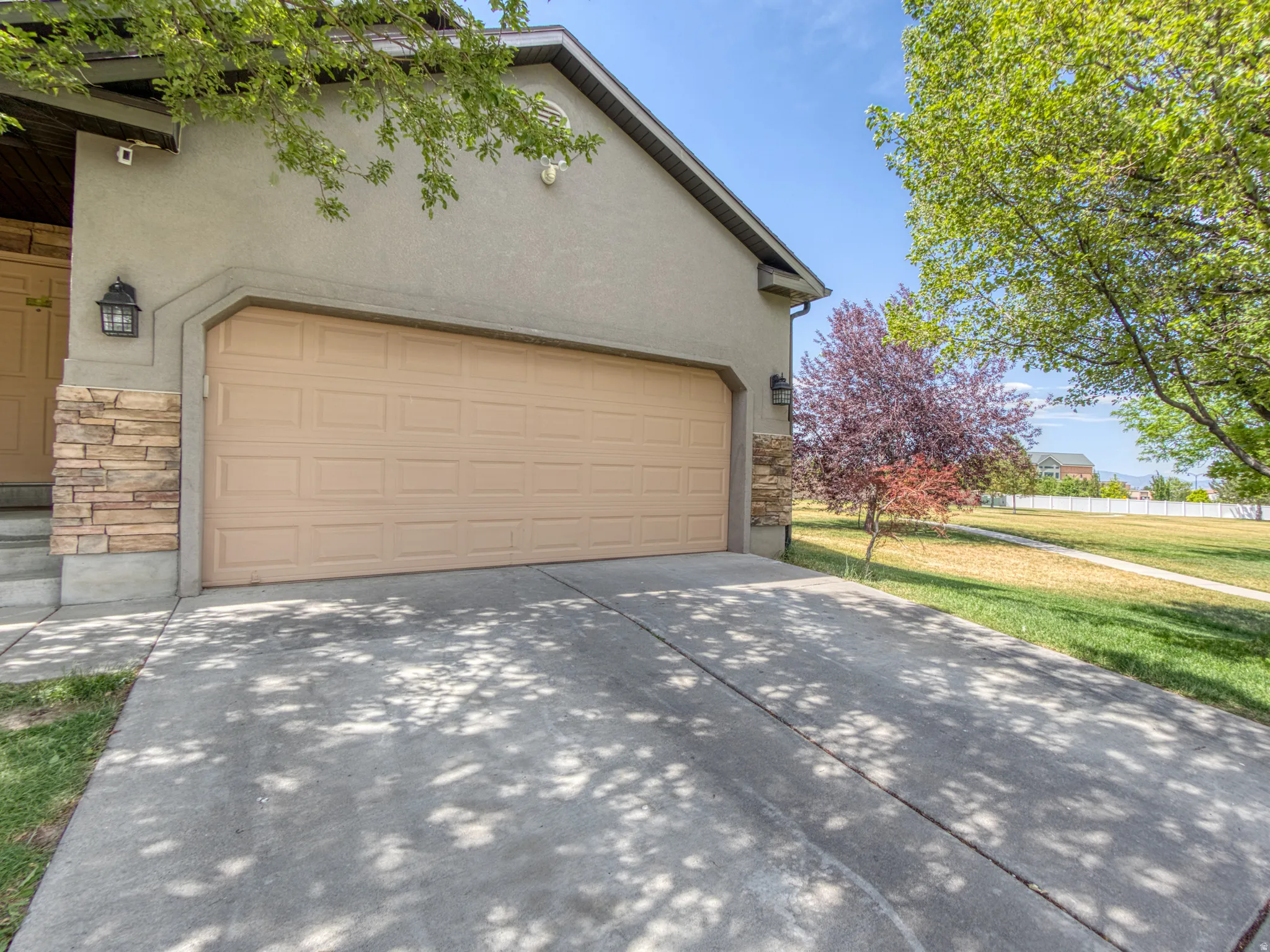 Attached two-car garage with a panel door, complemented by stacked stone veneer accents