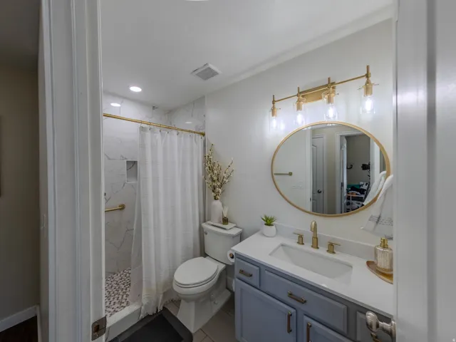 Bathroom featuring a shower with white marble-look tile, pebble flooring, and a built-in niche