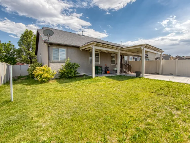 Expansive rear yard featuring a covered patio, concrete slab, and privacy fencing