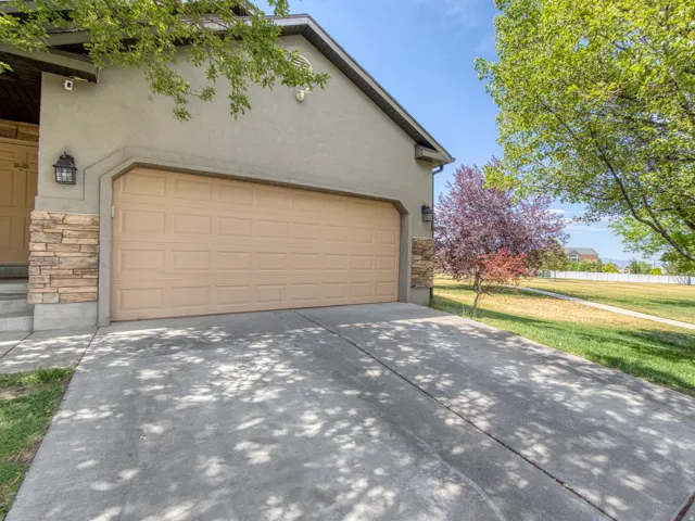 Attached two-car garage with a panel door, complemented by stacked stone veneer accents