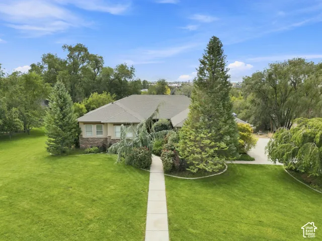 Exterior with a composite shingle roof, stone and stucco siding, mature landscaping, and an expansive lawn