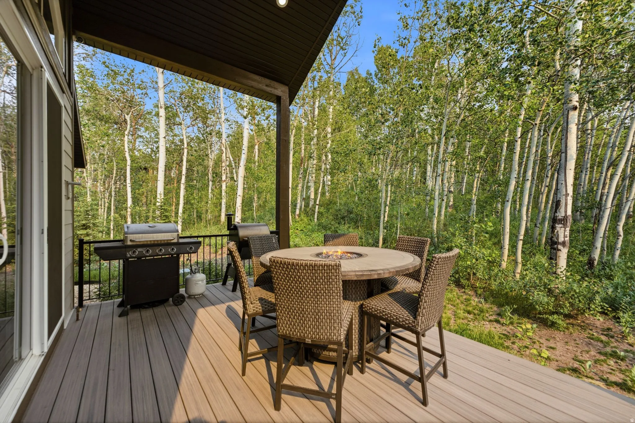 Spacious outdoor deck featuring composite decking, a dark metal railing, and a built-in fire pit table