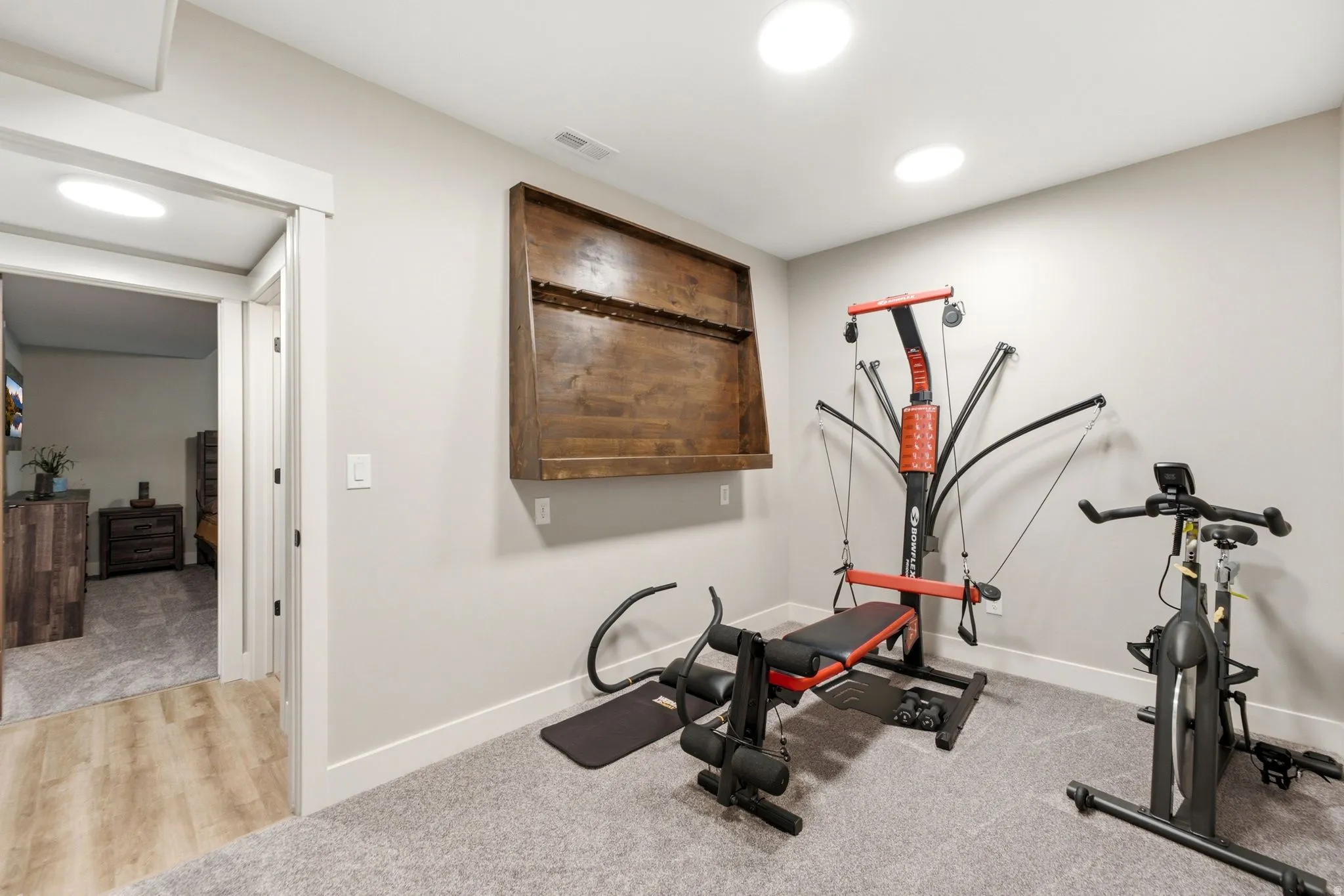 Carpeted room with recessed lighting and a built-in wall-mounted wooden display shelf