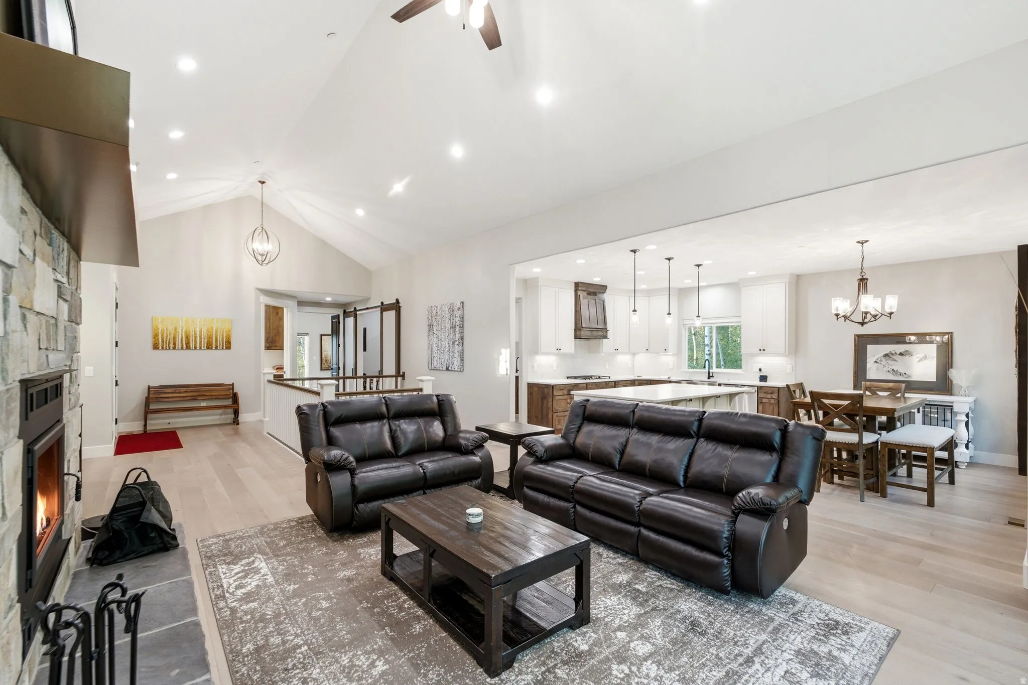 Open-concept living area with vaulted ceilings, recessed lighting, and wood-finish flooring