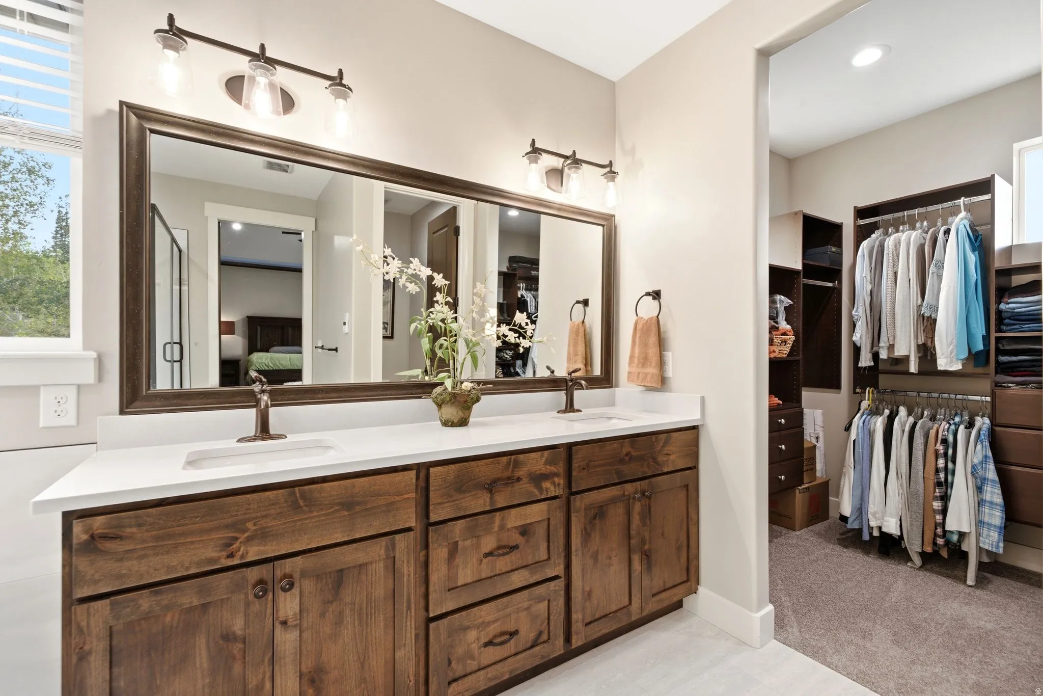 Dual vanity with undermount sinks, bronze faucets, and a large framed mirror