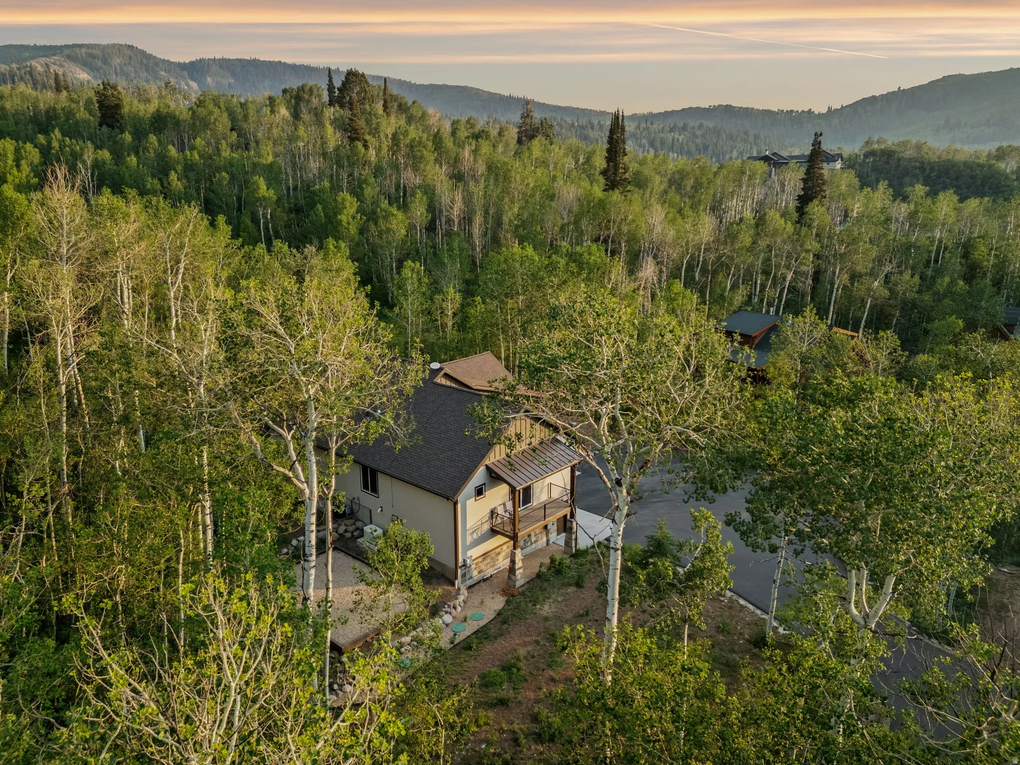 Mountain property featuring a multi-level structure with a dark shingle roof and a light-colored exterior