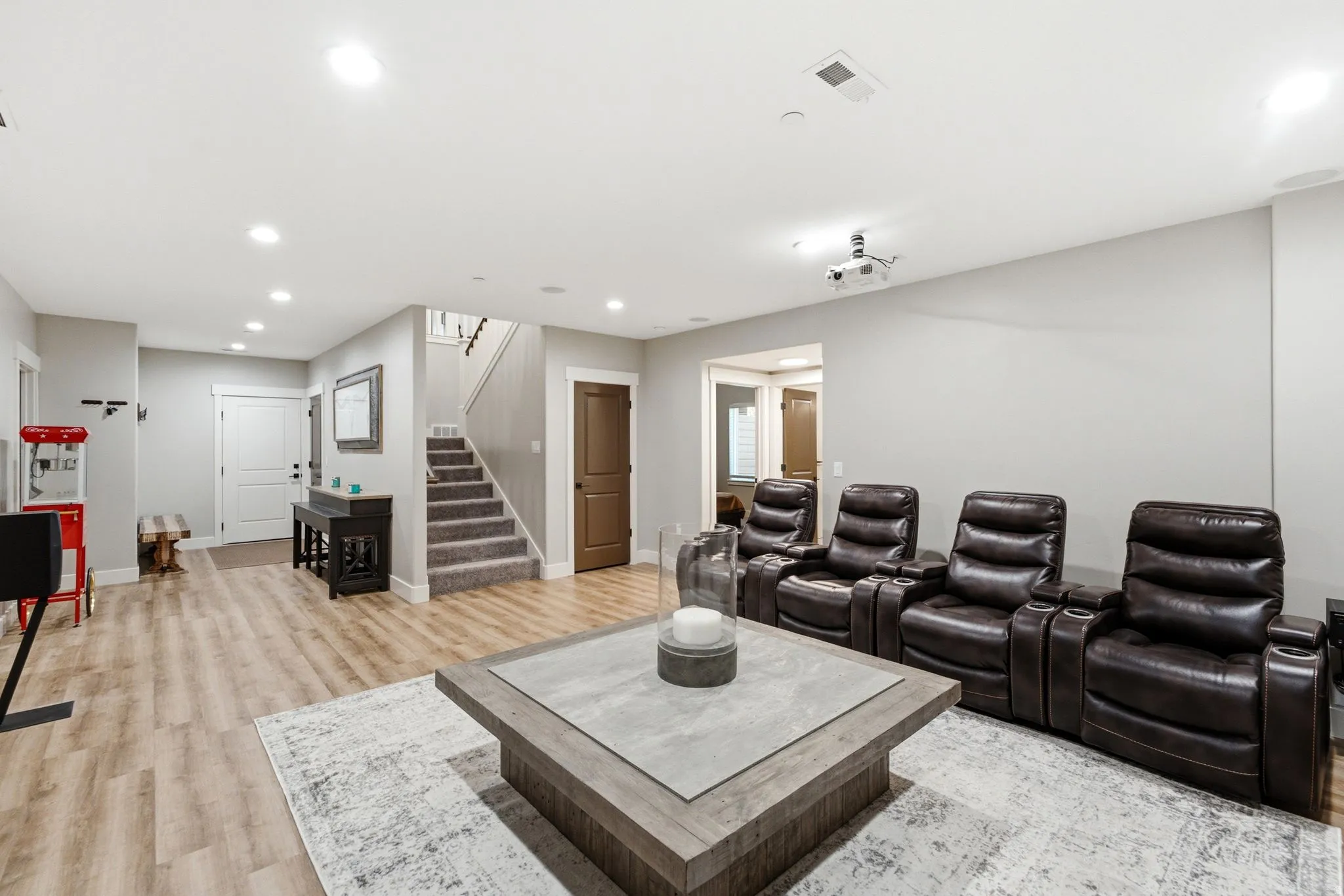 Spacious entertainment room featuring recessed lighting, light wood-finish flooring, and a ceiling-mounted projector