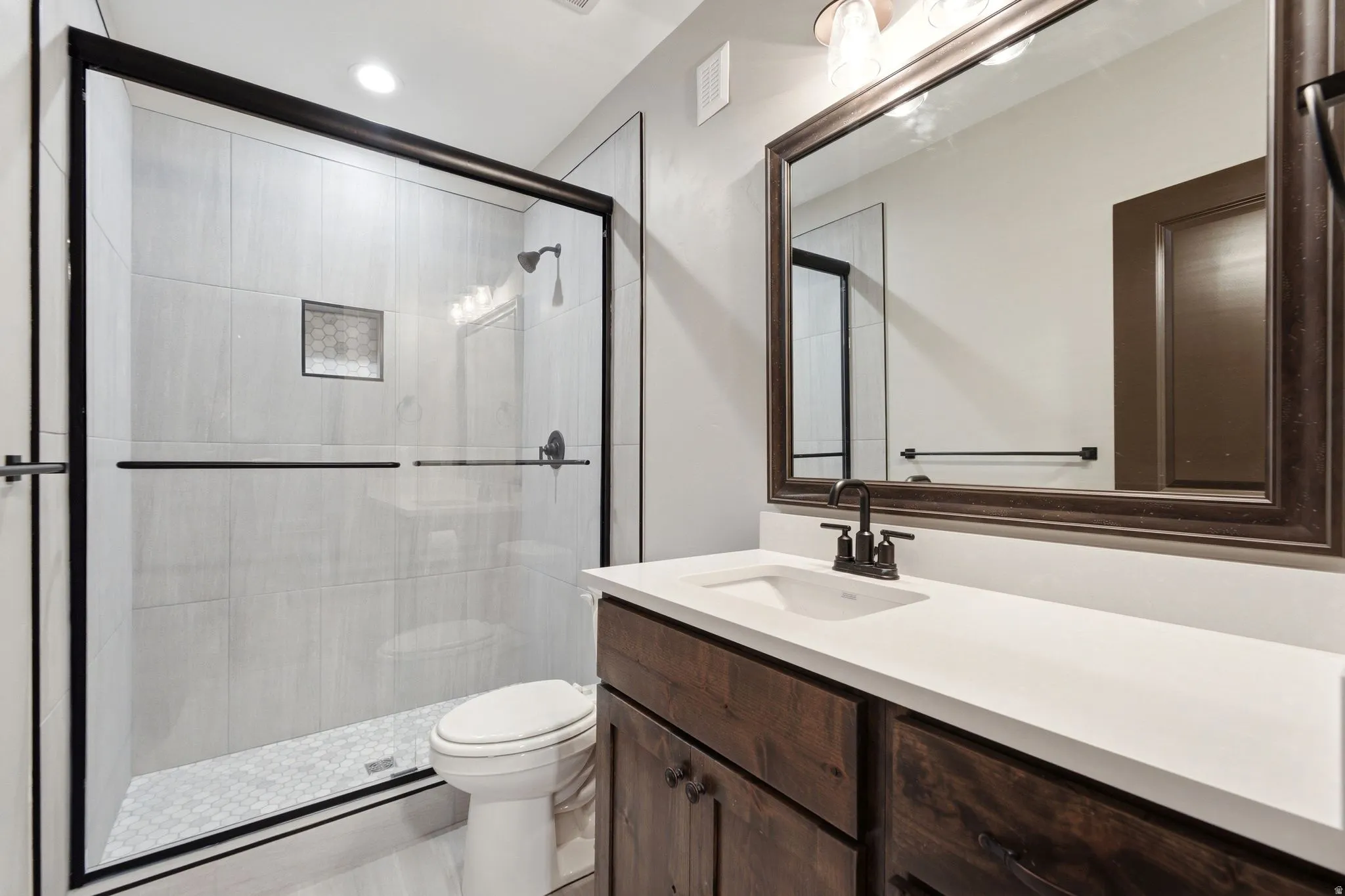 Bathroom featuring a glass-enclosed shower with tiled walls and a mosaic tile floor