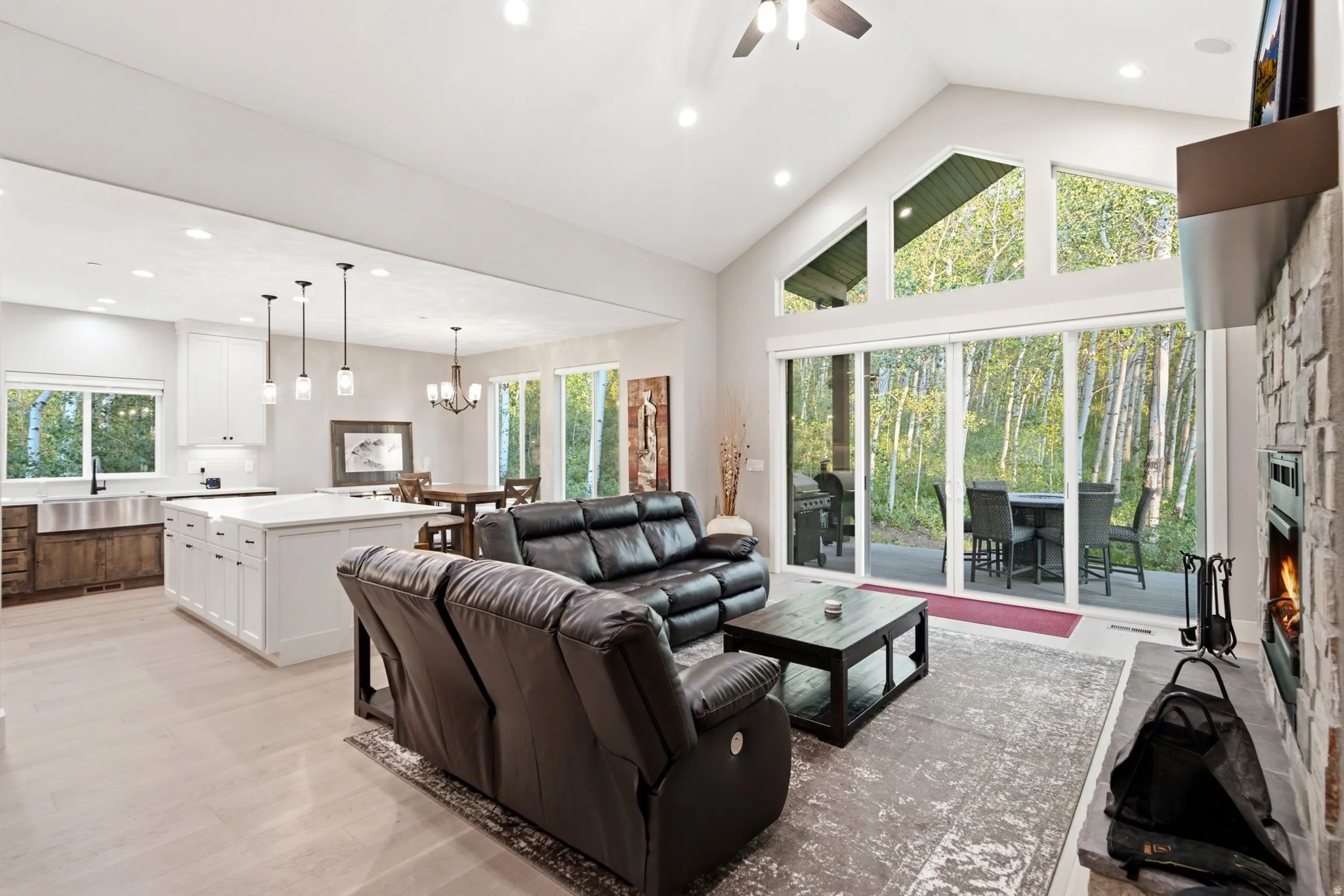 Spacious great room featuring vaulted ceilings, floor-to-ceiling windows, and a stone-faced fireplace