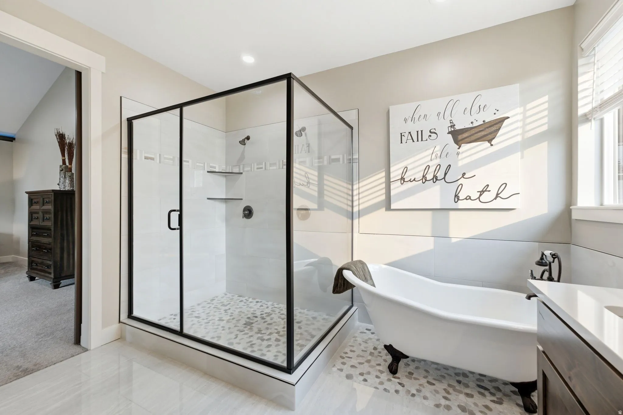 Spacious bathroom featuring a glass-enclosed shower with pebble-finish flooring and a freestanding clawfoot tub