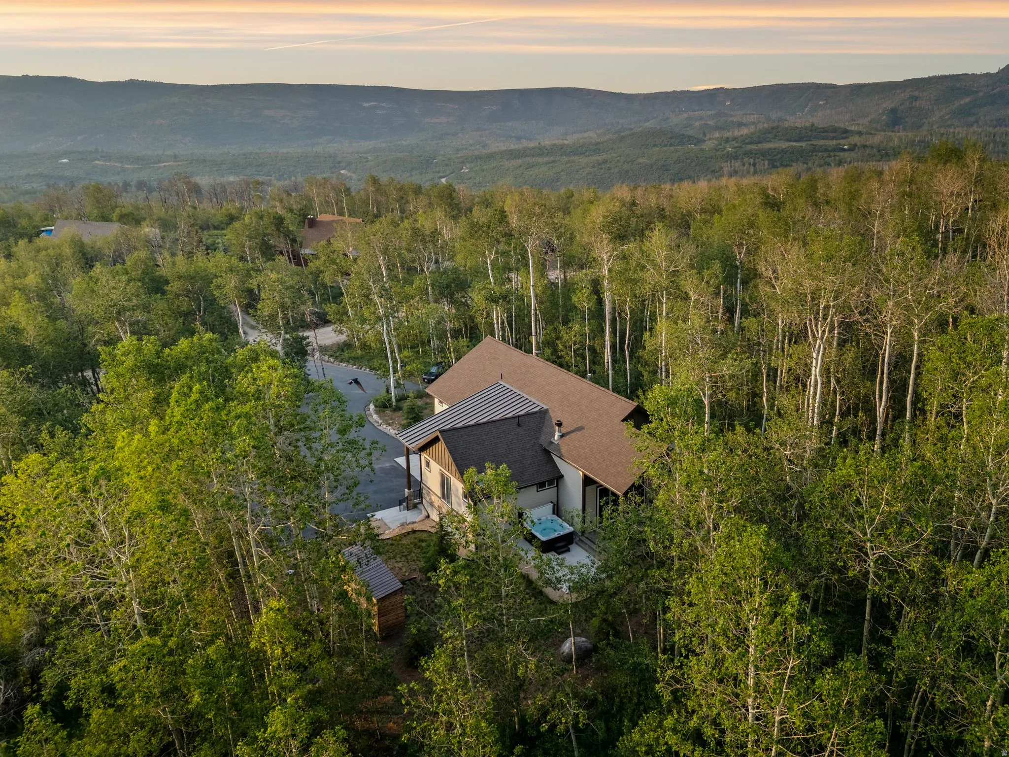 Wooded property featuring a multi-level residence with a tiered roofline