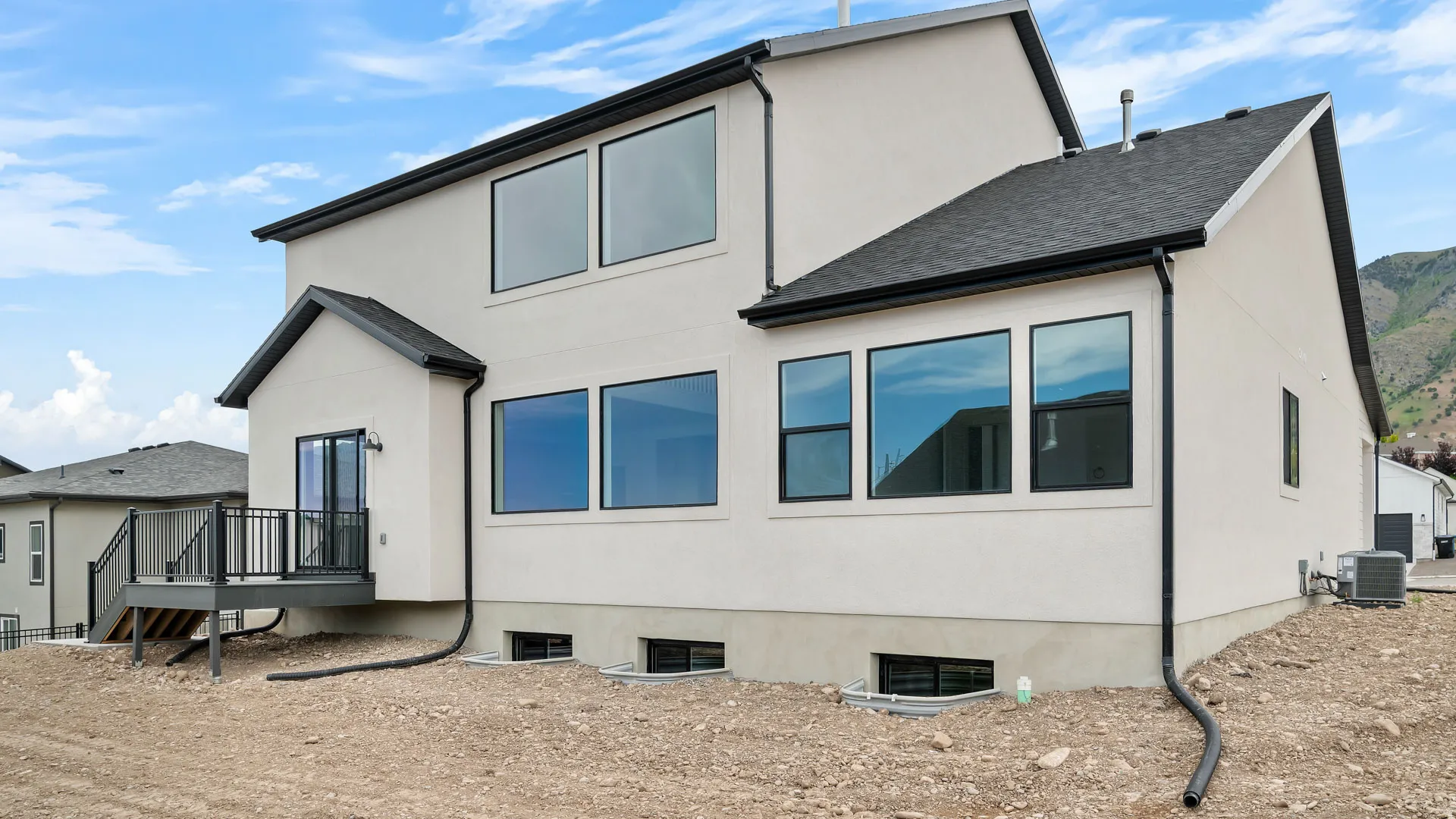 Contemporary stucco exterior featuring a rear deck with black railings