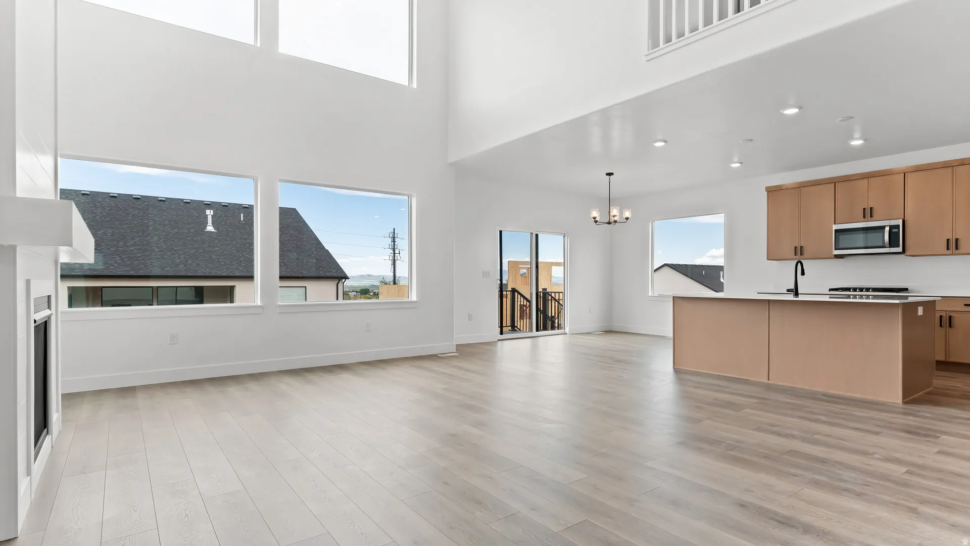 Expansive open-concept living space featuring high ceilings, wood-finish flooring, and a contemporary fireplace