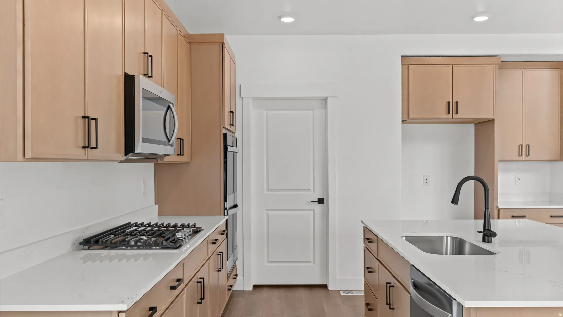 Modern kitchen featuring light wood-finish cabinetry and white countertops