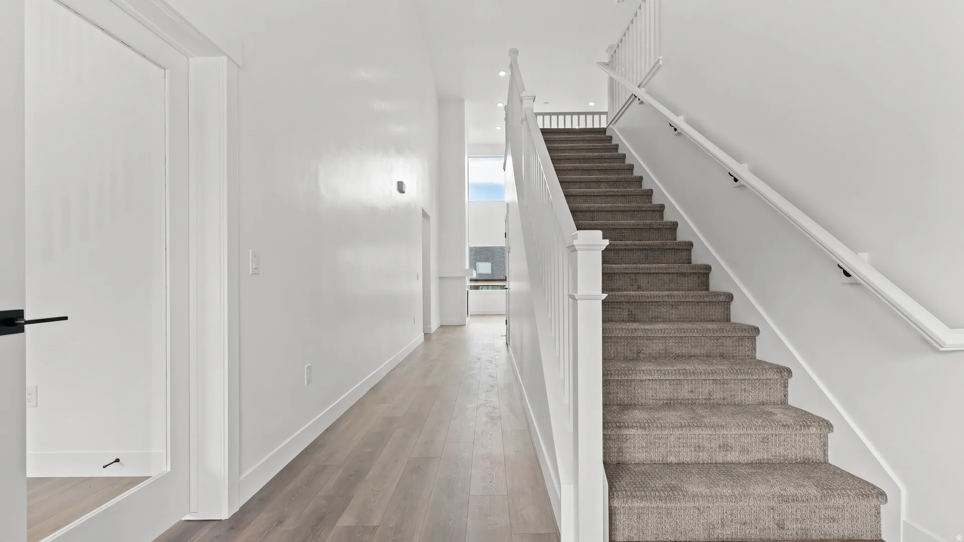 Staircase featuring carpeted treads, white risers, and white balusters with a matching handrail