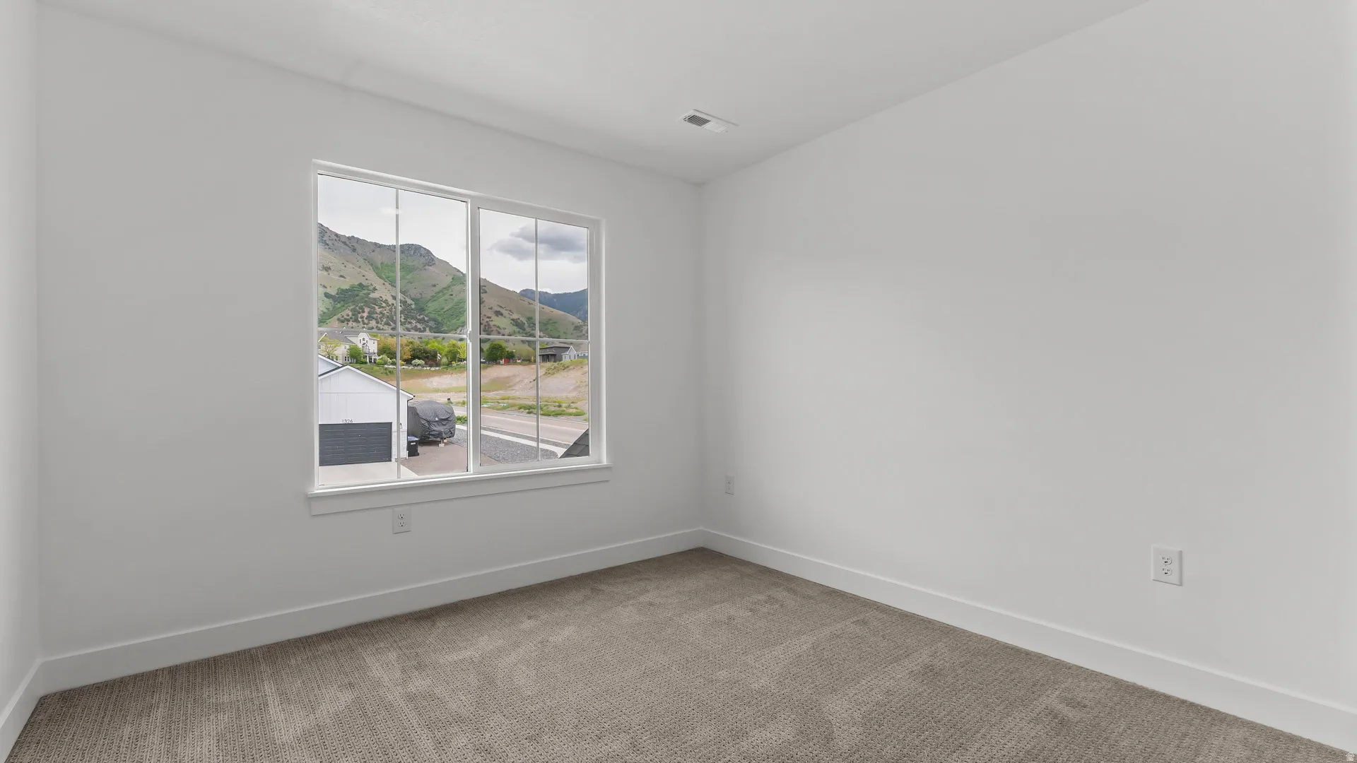 Spacious room featuring neutral carpeting, white wall finishes, and a large window providing mountain scenery