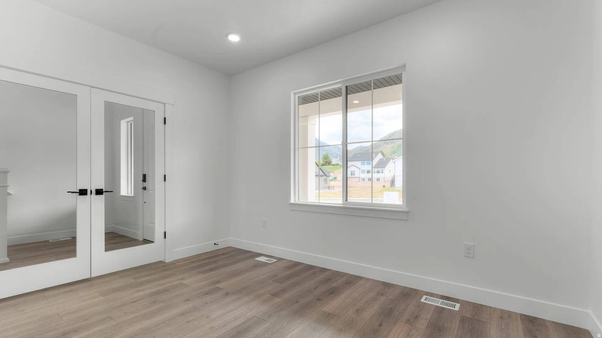 Room featuring wood-finish flooring, white baseboards, and bright white walls